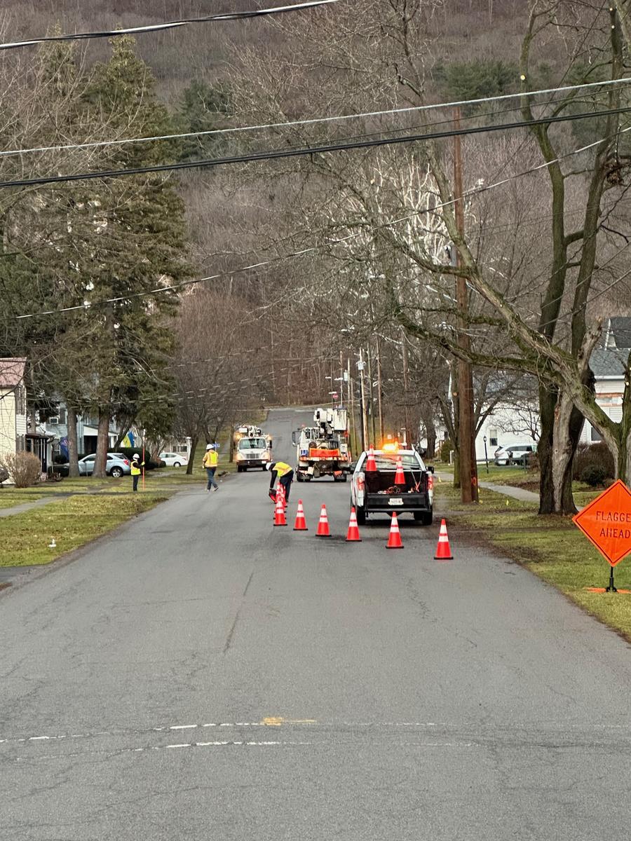 Cone taper and FLAGGER AHEAD sign set ahead of a utility crew on a residential street