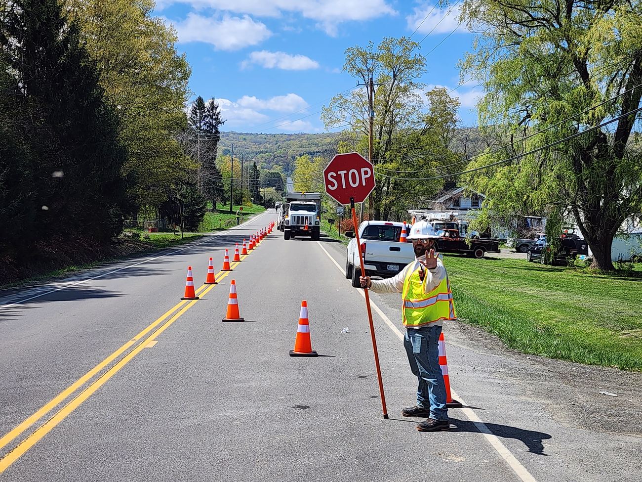 Howard Traffic Control flagger holding a stop paddle at a coned lane taper