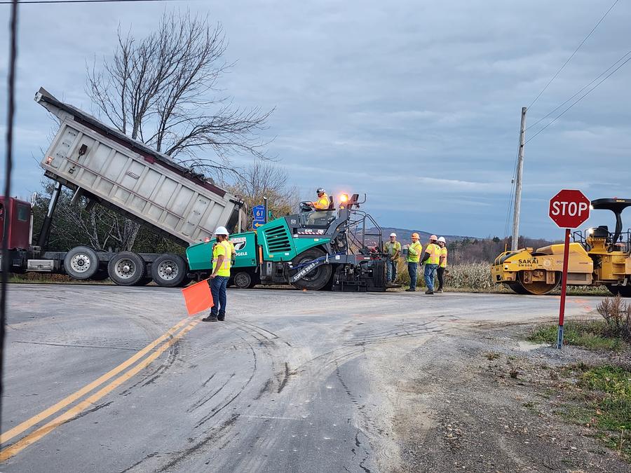 Flagger with an orange flag holding traffic at a paving operation