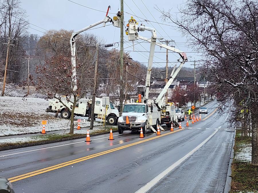 Winter work zone with bucket trucks, cones and a flagger on a snowy road